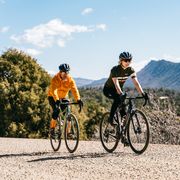 two people riding bikes on a gravel road